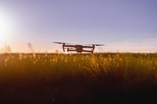 Drone em voo contra o pano de fundo de um pôr do sol em uma fazenda