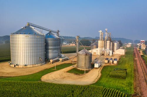 Grandes silos agrícolas e depósitos de grãos sob um céu claro.