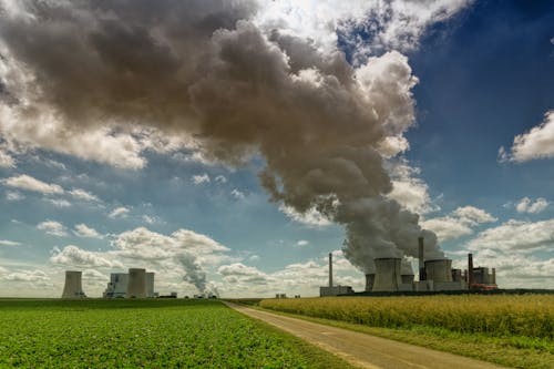 Uma instalação industrial com várias estruturas com uma quantidade significativa de fumaça saindo das chaminés.