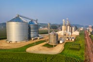 Grandes silos agrícolas e depósitos de grãos sob um céu claro.