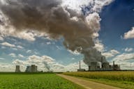 Uma instalação industrial com várias estruturas com uma quantidade significativa de fumaça saindo das chaminés.